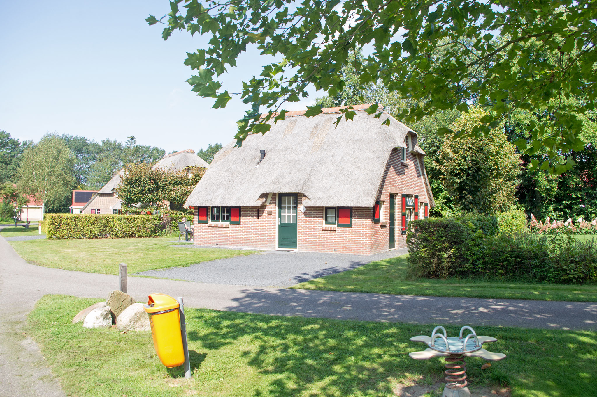 Voorkant en deel van omgeving vakantiehuis op zonovergoten dag